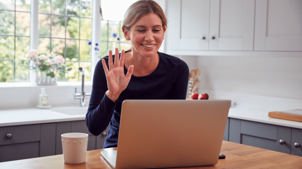 Woman smiling and waving to laptop