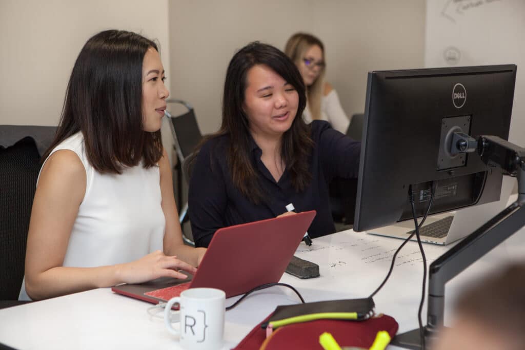 two female Rithm School students working at computers